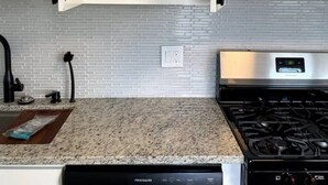 A kitchen with white cabinets, a stainless steel dishwasher, a gas stove, and a microwave.