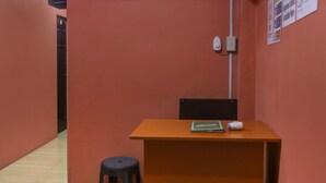 A room with a wooden desk, a black stool, and a wall-mounted light switch. - Solanos Transient House (Pasay)