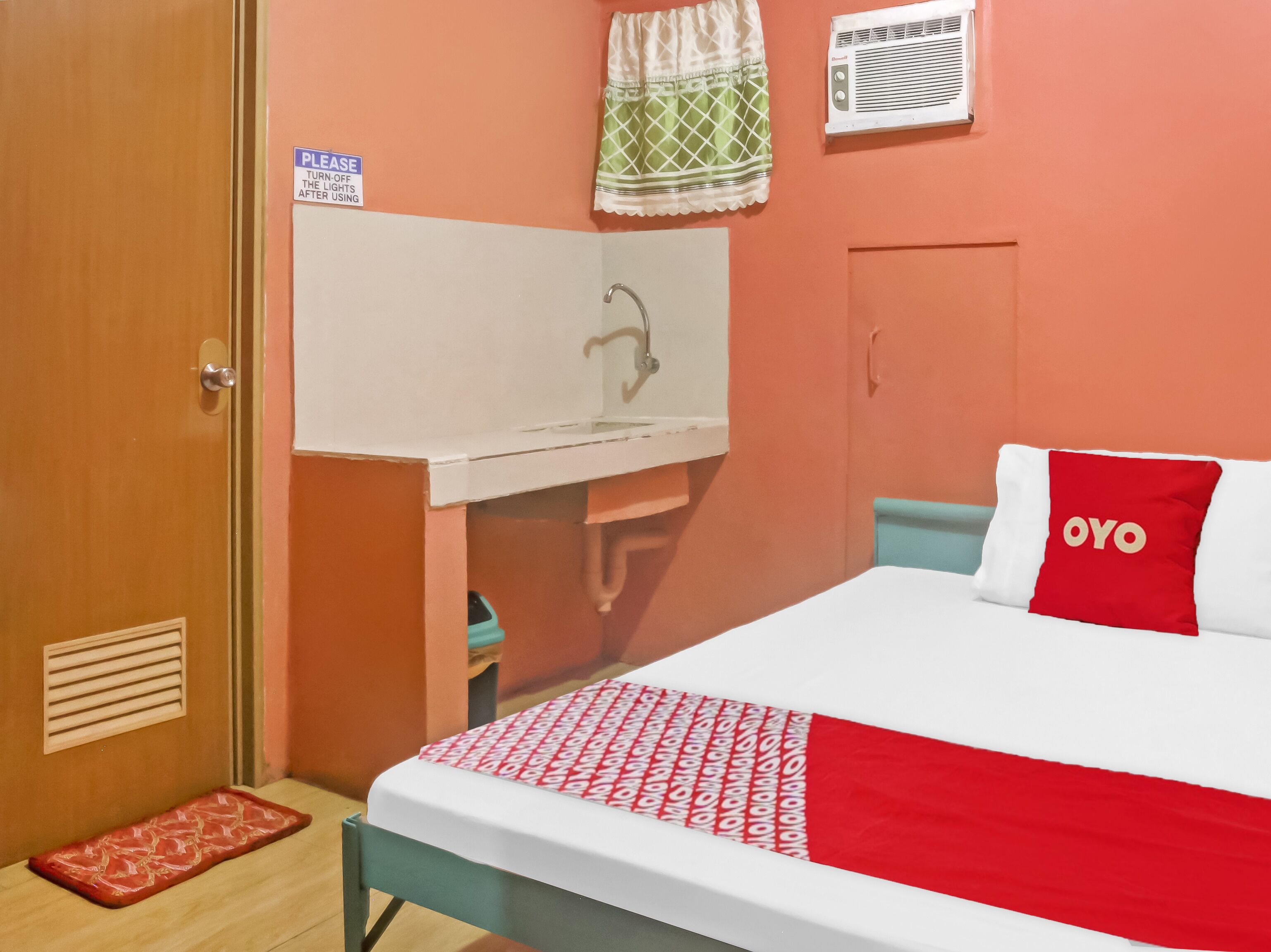 Una habitación con una cama, un pequeño escritorio, un espejo y una ventana con cortina.