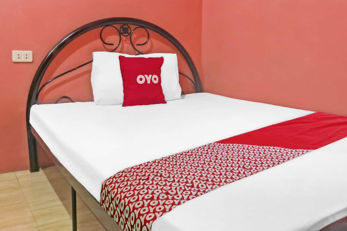 A bed with a white mattress, a red and white pillow, and a red and white patterned blanket.
