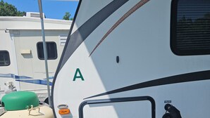Ein weißer Wohnmobilwagen mit braunem unteren Bereich, einem grünen Propanbehälter und dem Schriftzug 'SAVE PROPANE, INC.'