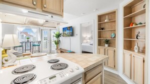 A modern kitchen with a white stove, wooden cabinets, and a tiled backsplash. - Ocean View Condo (Corpus Christi)