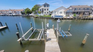 Un port de plaisance avec des bateaux amarrés, une jetée en bois et, au fond, des maisons résidentielles.