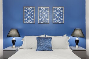 Relax in a spacious room with a large bed, two nightstands, and decorative panels above.