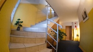 A staircase with beige tiles, a metal handrail, and a potted plant on the landing. - Romantic attic 1/2 room (Izola)