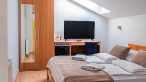 A bedroom with a bed, a desk, a TV, and a wardrobe. - Romantic attic 1/2 room (Izola)