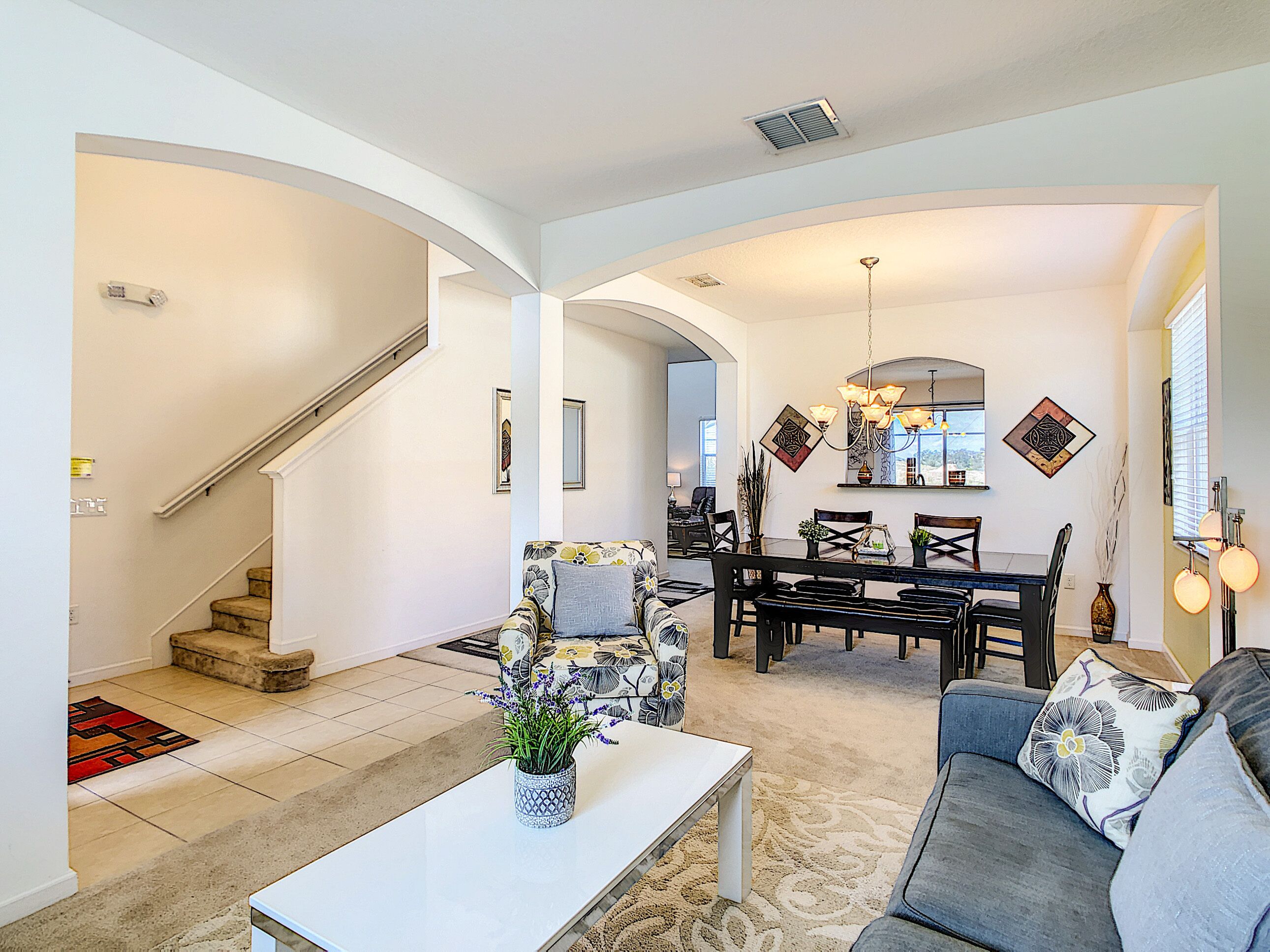 A spacious living room with a sofa, a coffee table, and a dining area with chairs and a table.