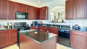 Una cocina moderna con armarios de madera oscura, encimera de granito, electrodomésticos de acero inoxidable y una isla grande.