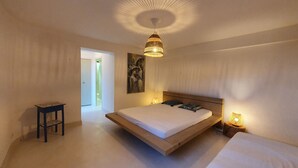 A bedroom with a large bed, a bedside table, a hanging light fixture, and a painting on the wall. - Magnificent pool villa between sea and mountains (Céret)