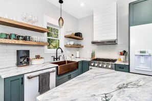 A modern kitchen with a marble countertop, a copper sink, and built-in appliances.