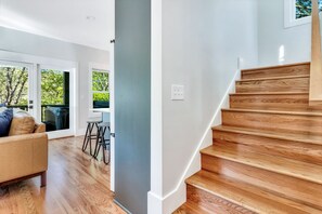 Un interior moderno con una escalera de madera, un sofá de cuero y un comedor con vistas a zonas verdes.