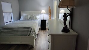 Ein Schlafzimmer mit Bett, Nachttisch, Lampe und Kommode.