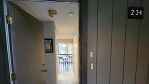 Ein Flur mit einer Tür, auf der die Nummer 234 steht, der zu einem Raum mit Fliesenboden und einem Fenster führt.