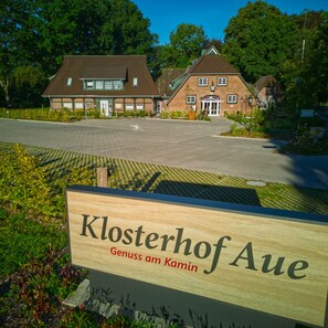 A sign for 'Klosterhof Aue' with a paved driveway and traditional buildings in the background.