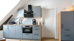 Eine moderne Küche mit grauen Schränken, einer Kaffeemaschine und einem Holztisch.