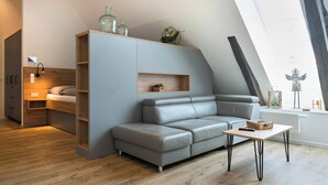 Ein modernes Schlafzimmer im Loft-Stil mit einer integrierten Schlafsofa, einem kleinen Tisch und einer Holzhängeschrank.