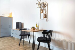 A modern kitchen with a dining table, two chairs, a cabinet, and a decorative wall piece. - The approx. 50 m², lovingly furnished 2-room apartment is located in the heart of Bad Zwischenahn and offers the perfect retreat for couples or solo travelers. The modern top-floor apartment impresses with its stylish design. (Bad Zwischenahn)