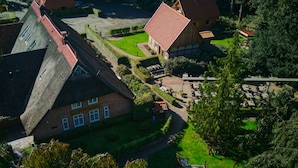 A traditional European-style building with a steeply pitched roof, surrounded by lush greenery and a well-maintained garden.
