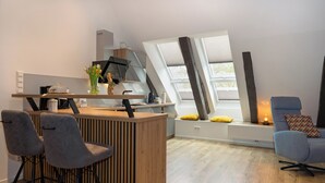 A modern kitchen with a wooden island, bar stools, and a built-in oven.