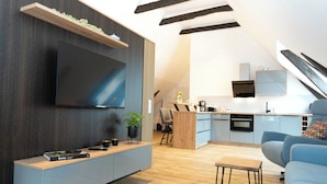 A modern living room with a flat-screen TV, a built-in bench, and a blue sofa.