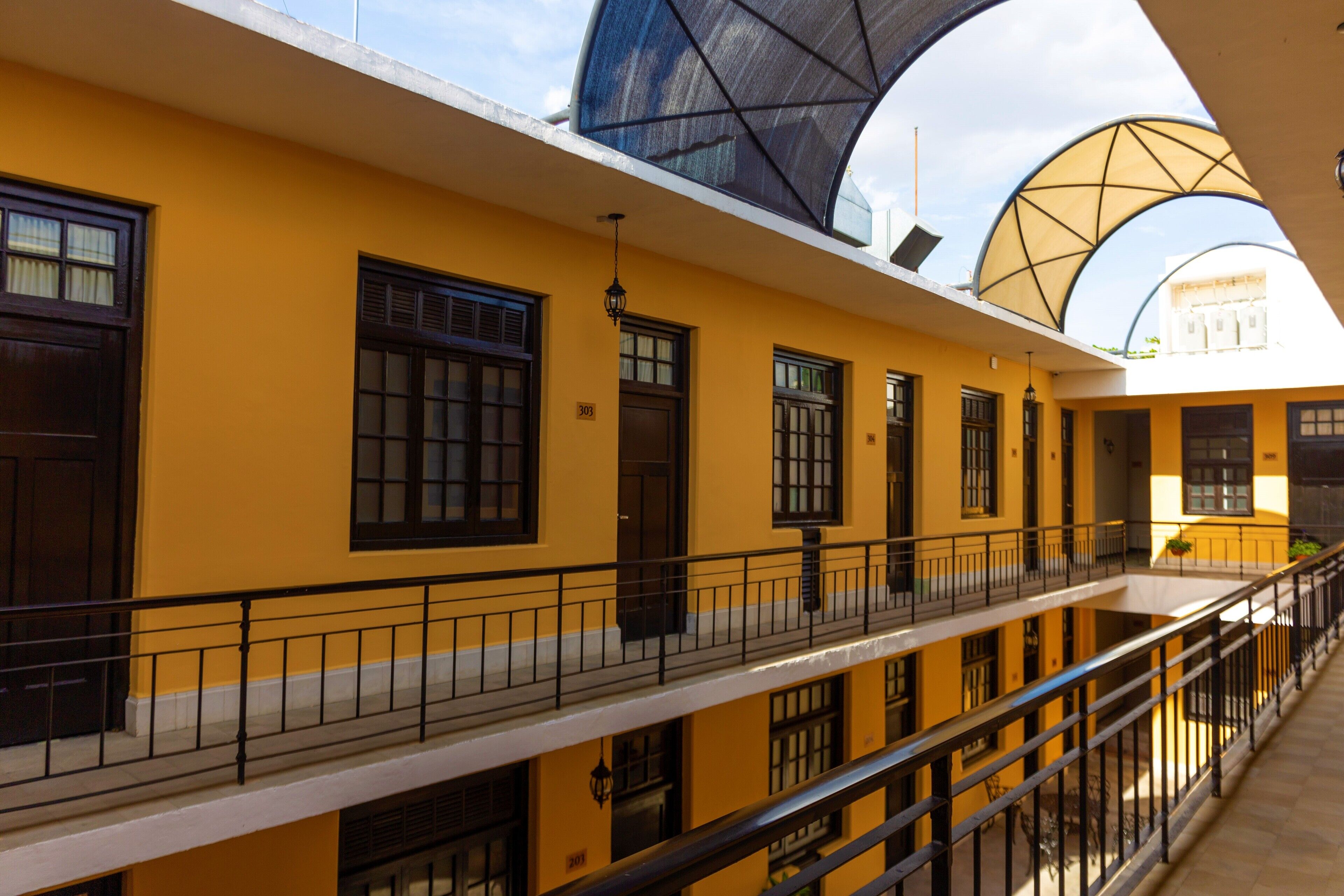 A multi-story building with yellow walls, black railings, and large windows.