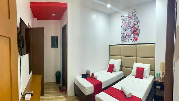A hotel room with two beds, a red ceiling, a wall art piece, and a wooden floor. - OYO 869 Jnv Dream Hotel (Subic)
