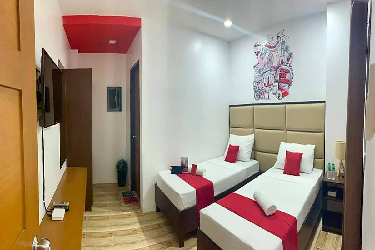 A hotel room with two beds, a red ceiling, a wall art piece, and a wooden floor.