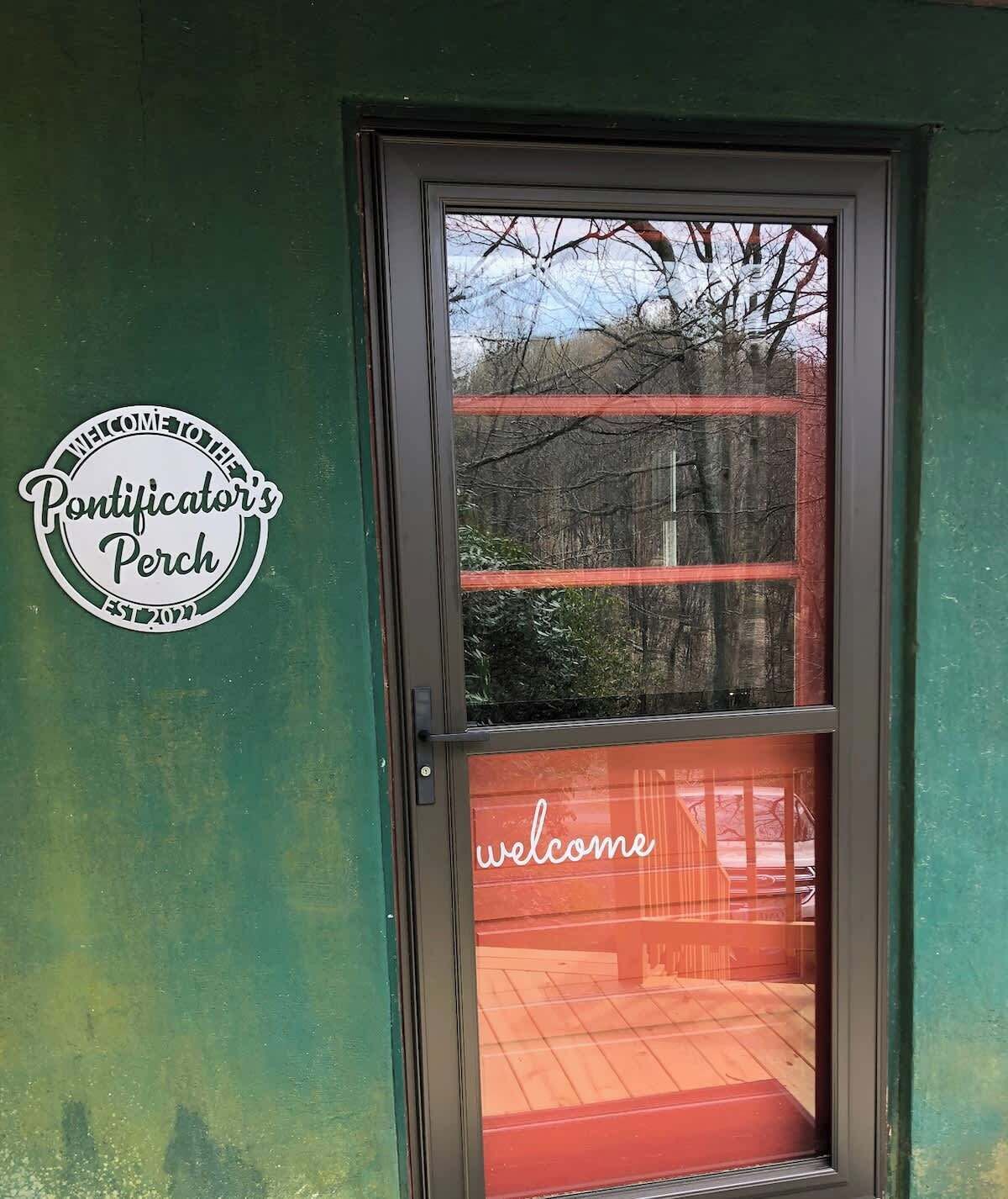 A door with a 'welcome' sign and a 'Pontificator's Perch' sign on the wall.