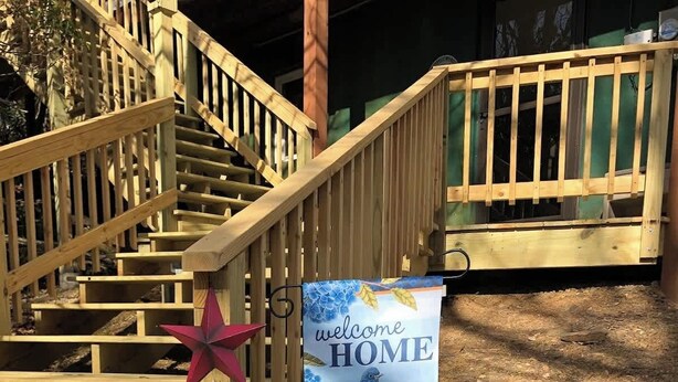 A wooden staircase leading to a building with a 'welcome HOME' sign.