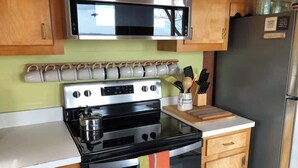 A compact kitchen with a stove, oven, microwave, and a refrigerator.