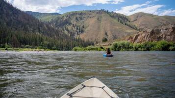 A kayaker on a river with mountains in the background.