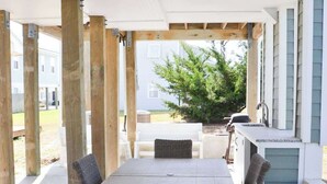 An outdoor patio with a table and chairs, a grill, and a view of a house. - Unique 3BR Home with great views Beach Access (Atlantic Beach)