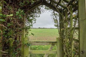 Enter a serene rural landscape through this traditional gate, leading to a vast, well-manicured field.