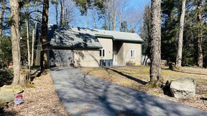 A single-story house with a garage, surrounded by a forest. - NEW!! Pocono!! Family Friendly, Hot tub, Fireplace (Tobyhanna)