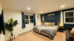A bedroom with a bed, bedside tables, a window with curtains, a wall with dreamcatchers, and a potted plant. - NEW!! Pocono!! Family Friendly, Hot tub, Fireplace (Tobyhanna)