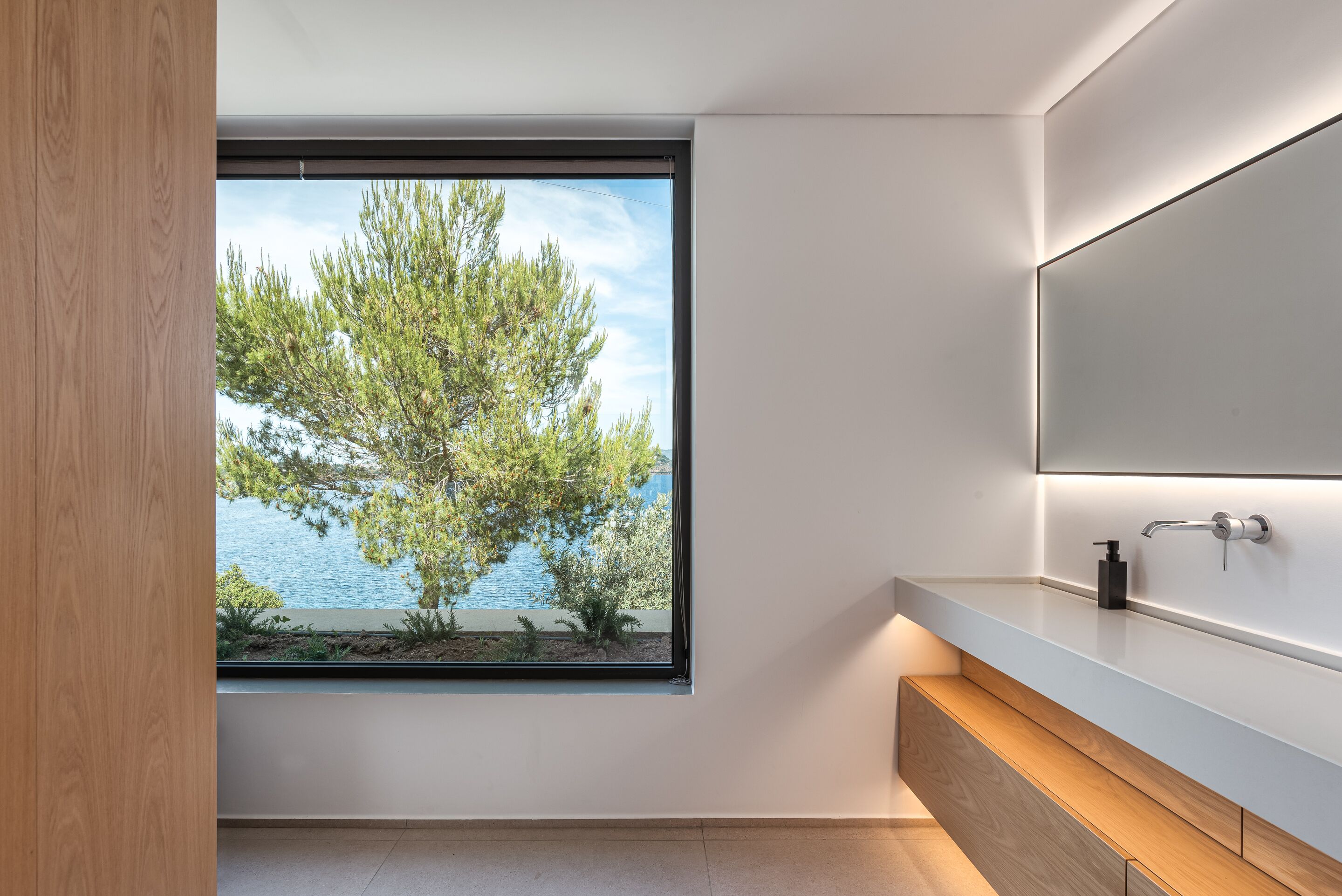 Une salle de bain moderne avec une grande fenêtre, un meuble-lavabo en bois et un miroir.