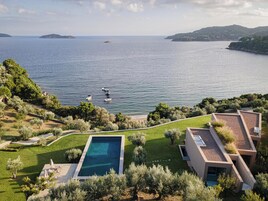 Una villa moderna con piscina, jardín ajardinado y vistas al mar.