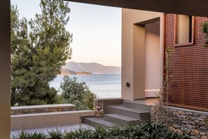 A modern outdoor area with steps leading to a stone wall, overlooking a body of water and distant mountains. - Pelagoon Skiathos (Skiathos)