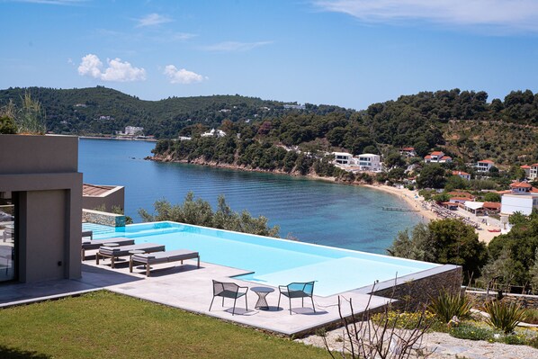 A modern pool area with lounge chairs and a view of the sea and hills. - Pelagoon Skiathos (Skiathos)