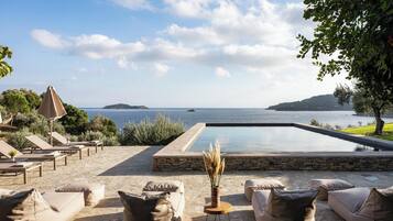 Zona de piscina con sillones reclinables y vista al mar.