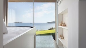 Un dormitorio moderno con un ventanal grande con vistas a un paisaje costero.
