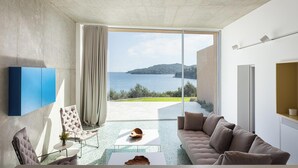Una sala de estar moderna con un amplio ventanal corredera que da a un balcón con vistas al mar.