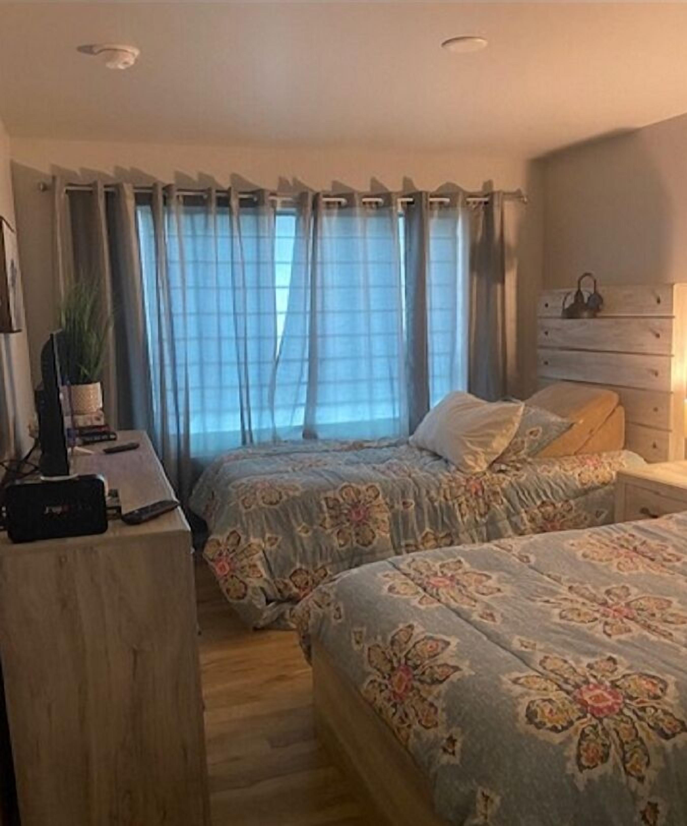 Une chambre avec deux lits, un bureau avec un ordinateur et une commode.