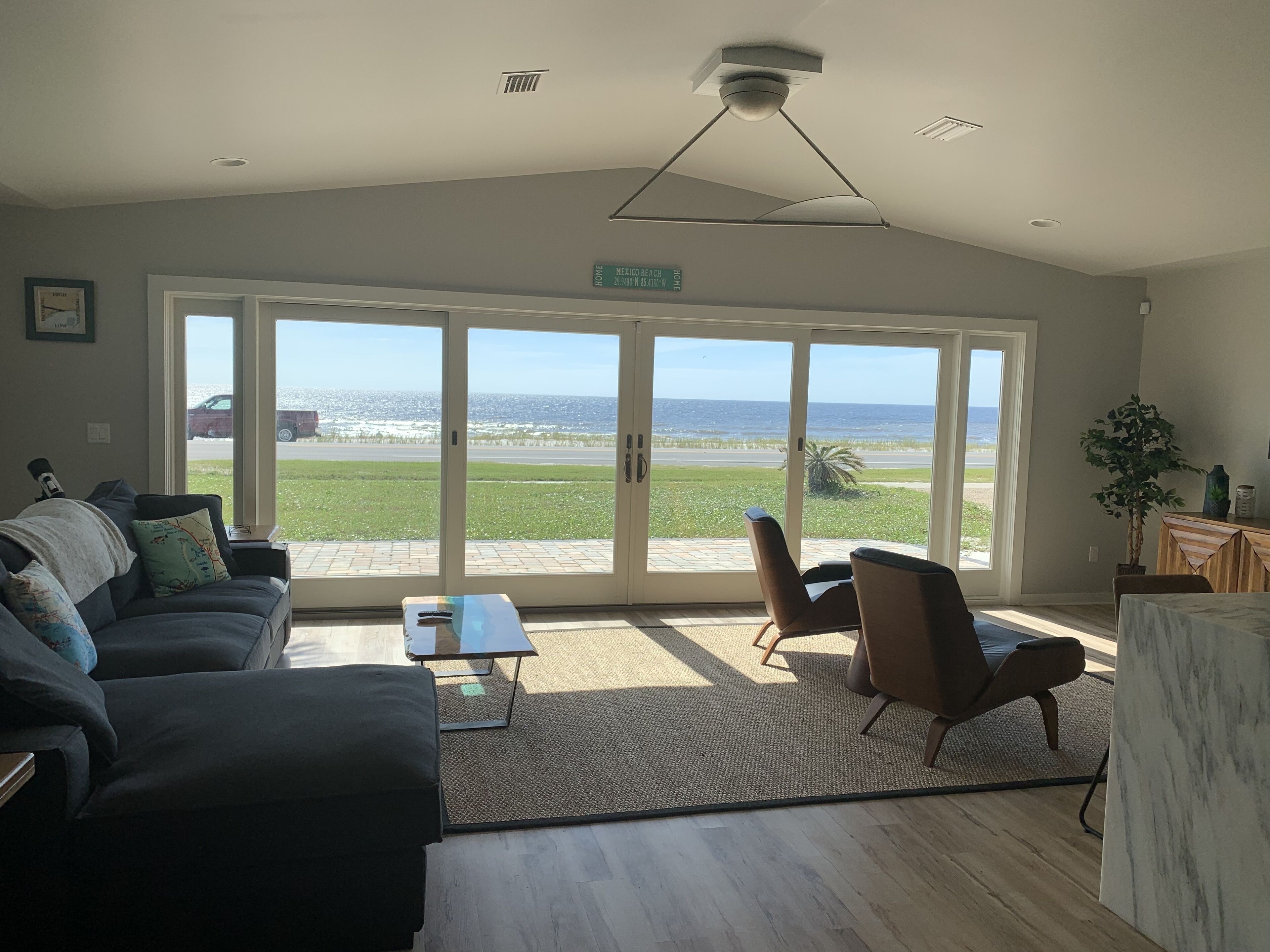 A spacious living room with a large sliding glass door leading to a balcony with a view of the beach.