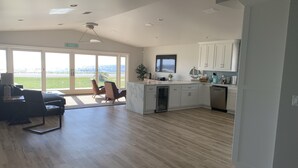 Une cuisine spacieuse avec des meubles blancs, un lave-vaisselle encastré et une grande fenêtre donnant sur un paysage verdoyant.