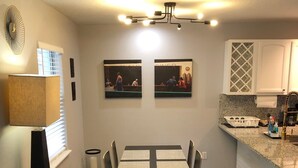 A modern kitchen with a dining table, chairs, and artwork on the wall. - Amazing Five-Star Luxury Thornton Park two Bedroom Apt - close to Kia Center. (Orlando)