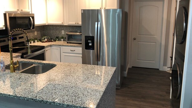 A modern kitchen with granite countertops, stainless steel appliances, and white cabinetry. - Amazing Five-Star Luxury Thornton Park two Bedroom Apt - close to Kia Center. (Orlando)