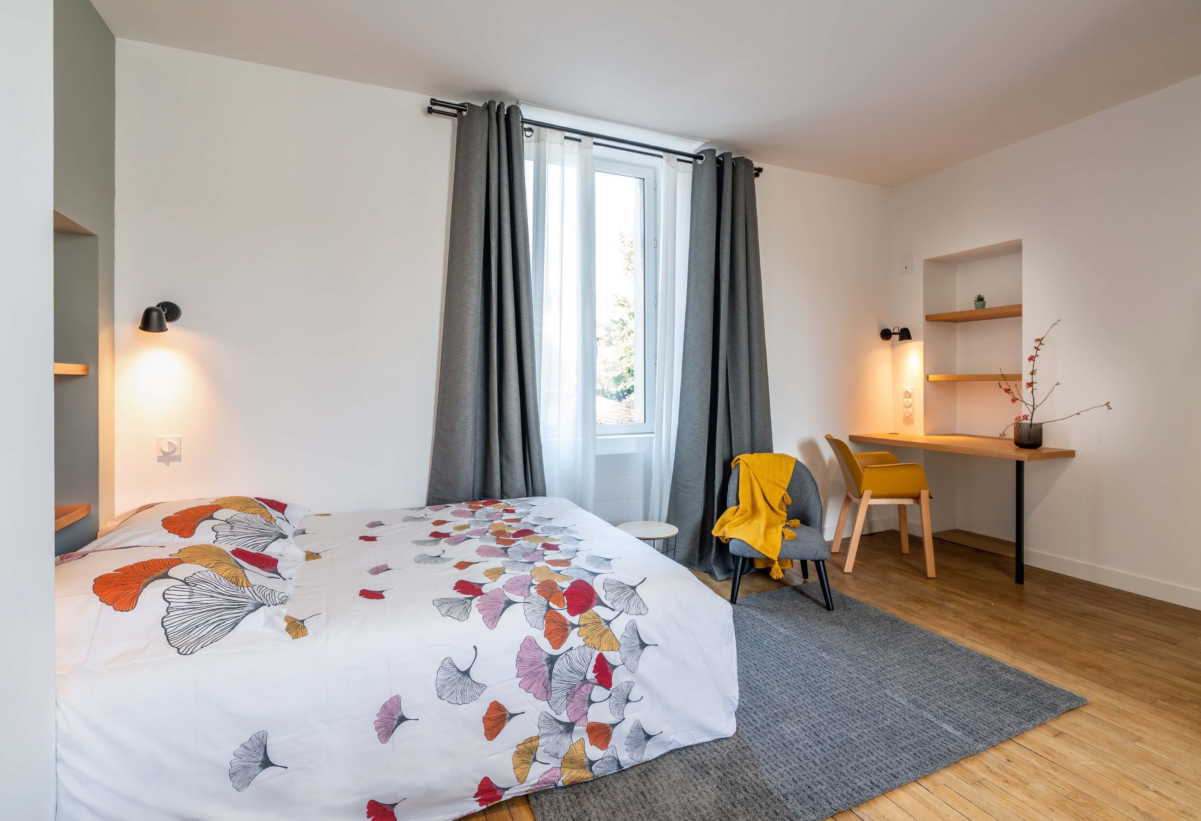 A bedroom with a bed, a desk, and a chair.
