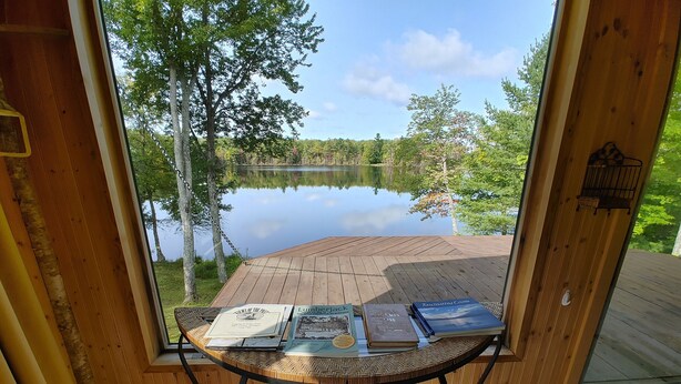 A wooden deck with a table holding books and a bird feeder.