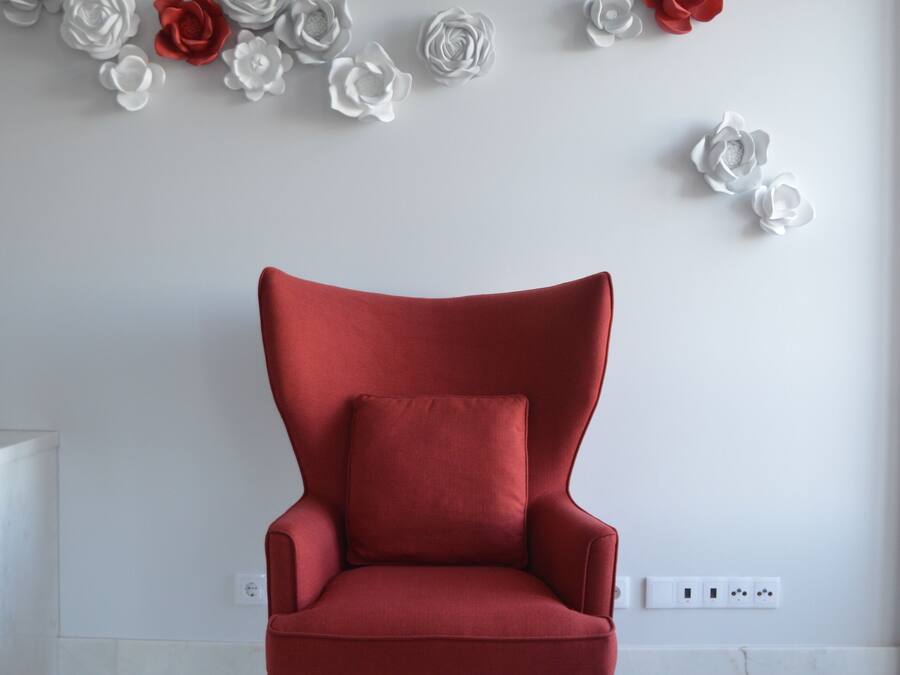A red armchair in a room with a white wall and a white floor.